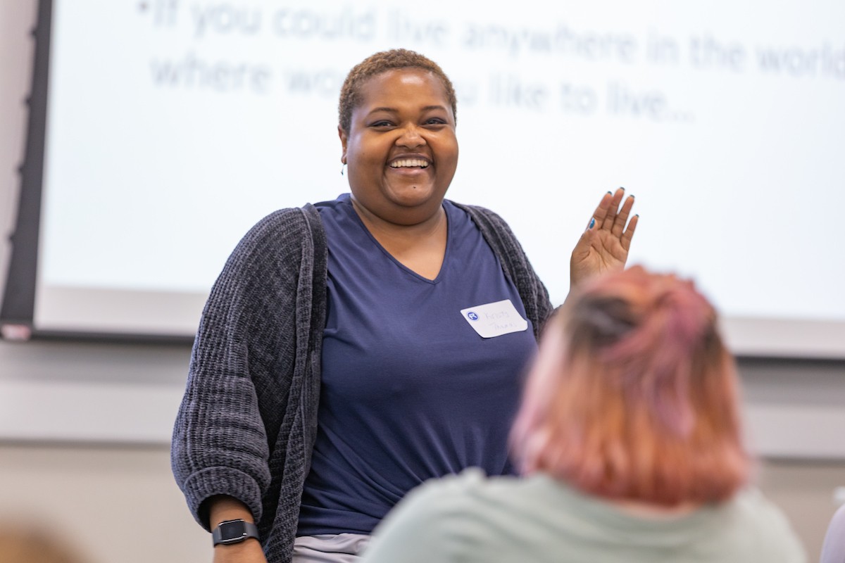 An Ed.D. graduate student smiles at the camera in front of a whiteboard