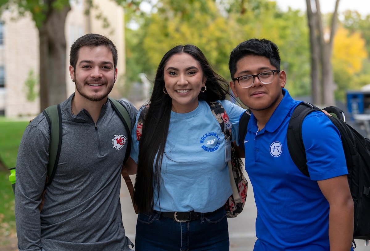 Three students smiling at camera on Rockhurst campus wearing Rockhurst shirts