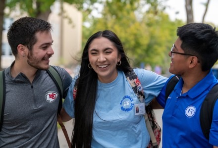 Two guys and a girl share a laugh in the middle of campus