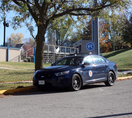 Security Car next to tree and baseball bleachers
